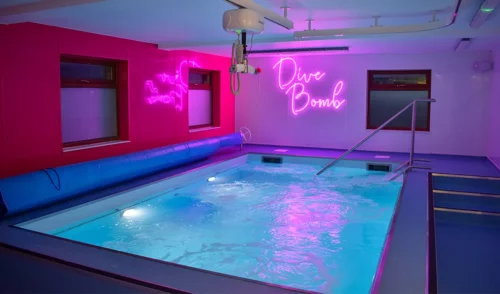 A sensory hydrotherapy pool with bright lights, air jets, and an overhead hoist.