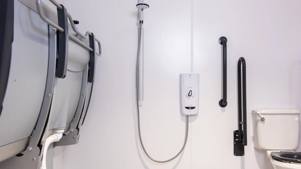 Wall-mounted height-adjustable changing bench and shower unit at Lloyds Banking Group Changing Places